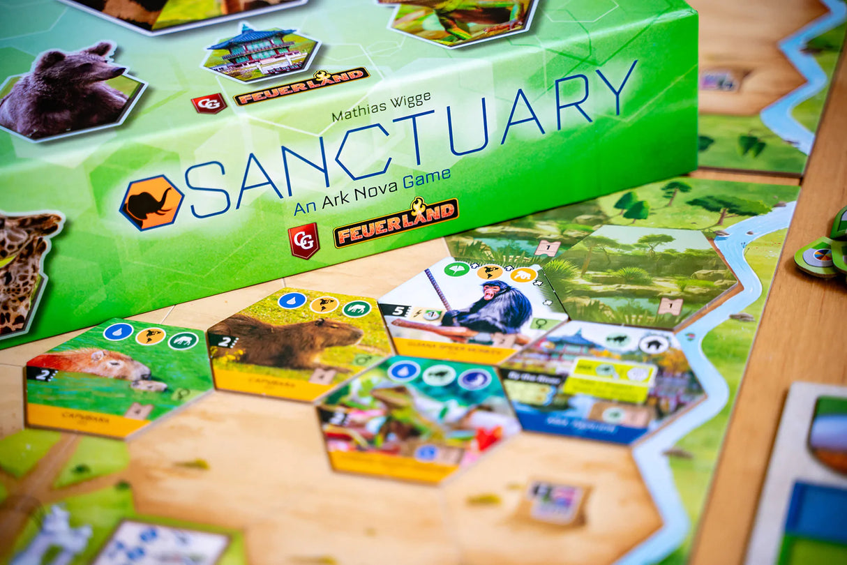 Board game box for 'Sanctuary' by Ark Nova on a table with game pieces.
