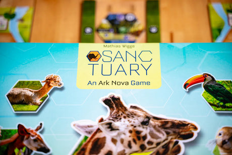 Board game pieces with animals and 'Sanctuary' logo on a blue background